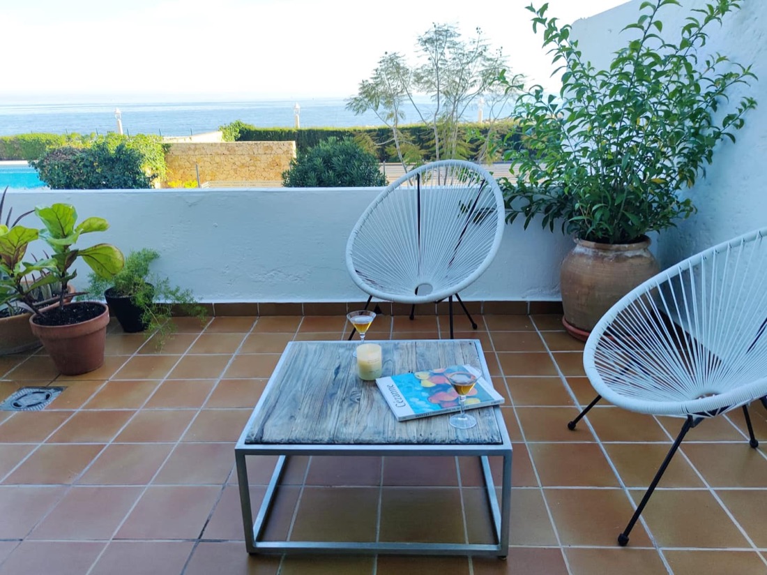 Zonnig terras met loungehoek om te ontspannen met uitzicht op zee en tuin.