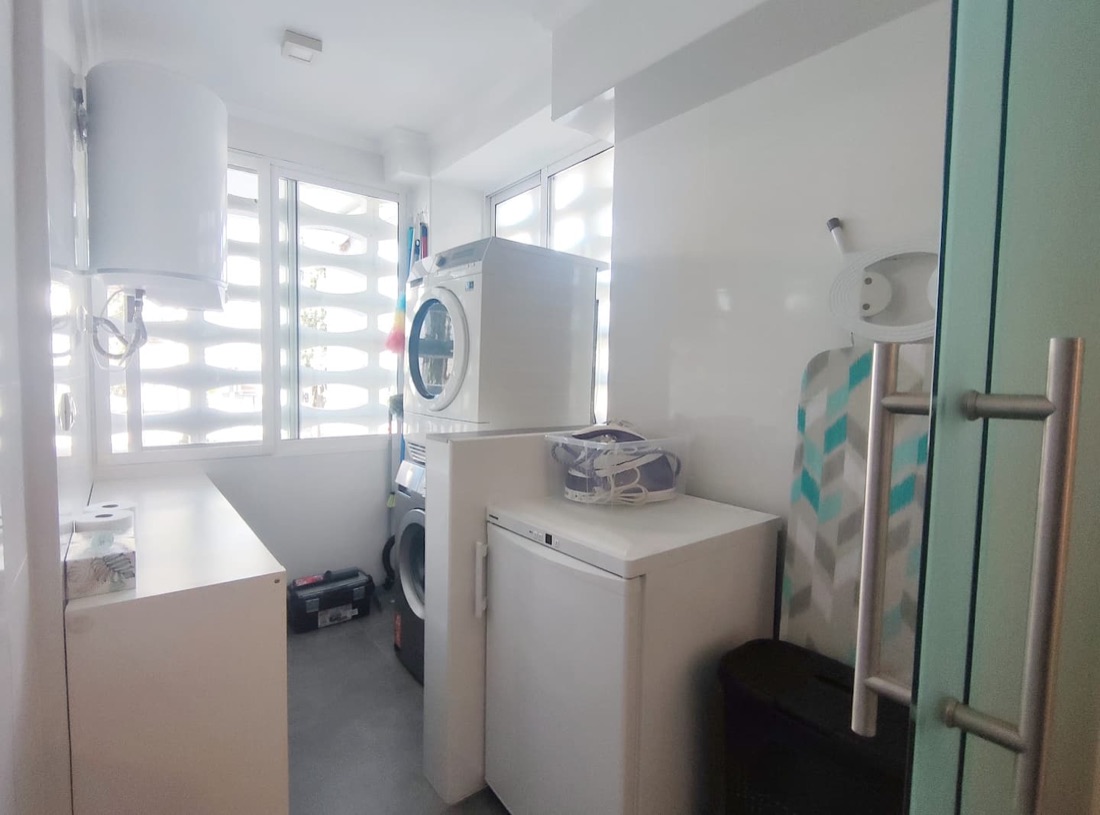 Wasruimte met wasmachine, droger, vriezer, boiler en schoonmaak benodigheden, stofzuiger, stoomstrijkijzer en strijkplank.
