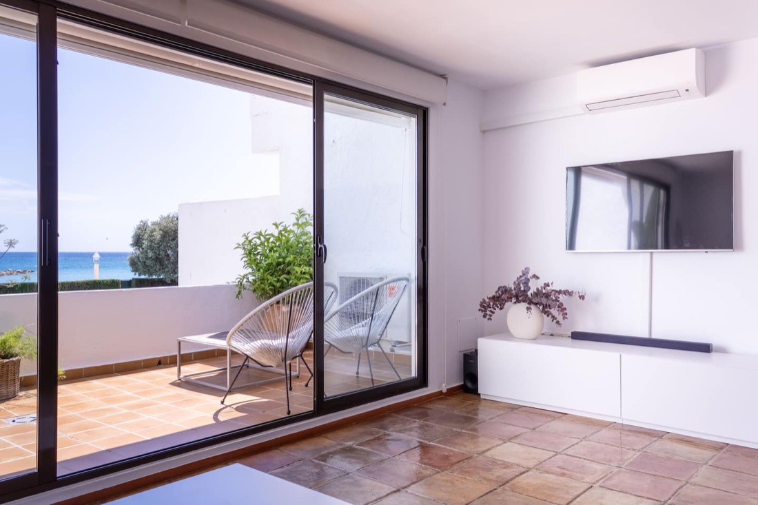 Woonkamer met airconditioning en schuifdeuren naar het terras.